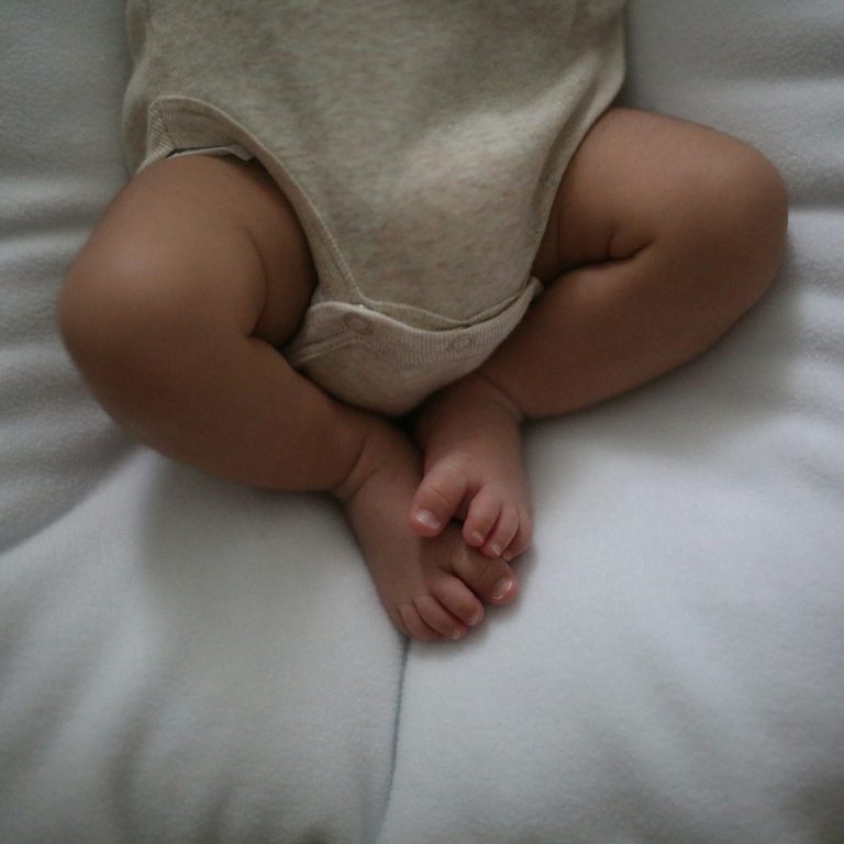 A baby in an oatmeal ribbed cotton bodysuit