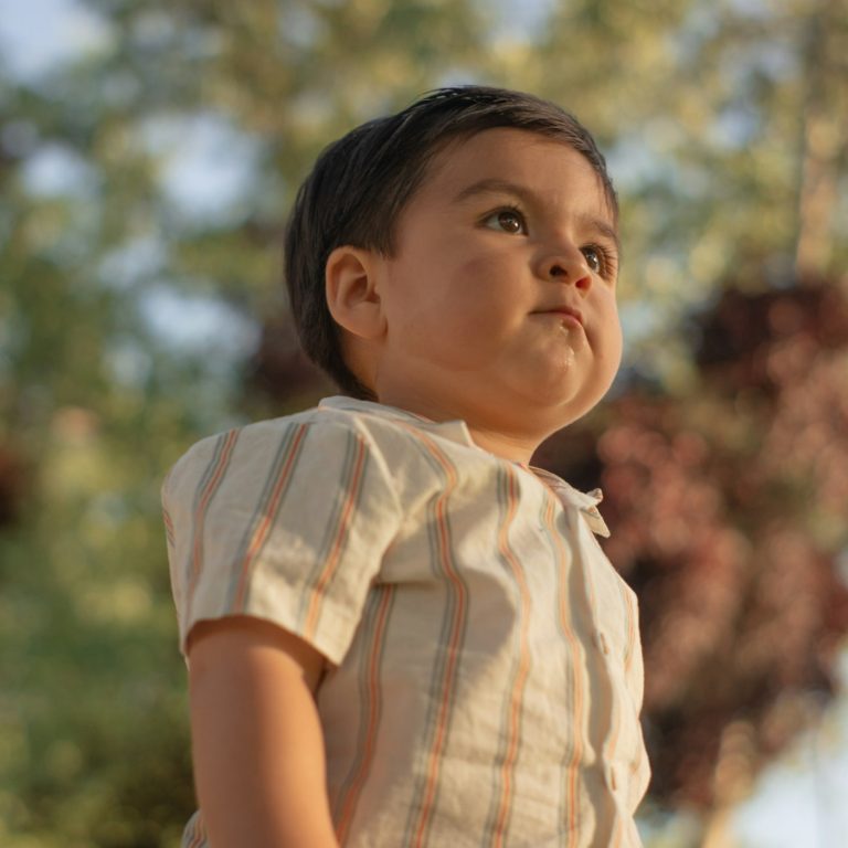 A toddler in a cream striped short-sleeve shirt